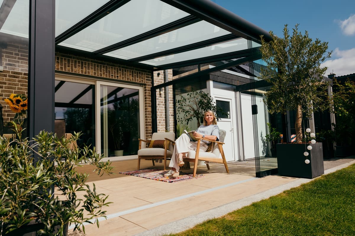 Een moderne veranda met glazen dak creëert een lichte en ontspannen sfeer in de tuin.