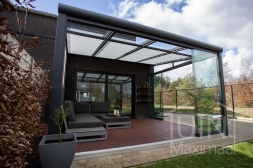 Moderne Gumax® Terrasoverkapping in mat antraciet van 4,06 x 4 meter met glazen dakplaten inclusief Gumax zonwering, LED verlichting, glazen schuifwanden en een glazen spie