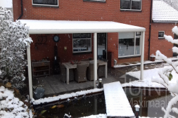 Moderne Gumax® Terrasoverkapping in mat wit aan huis, in de sneeuw